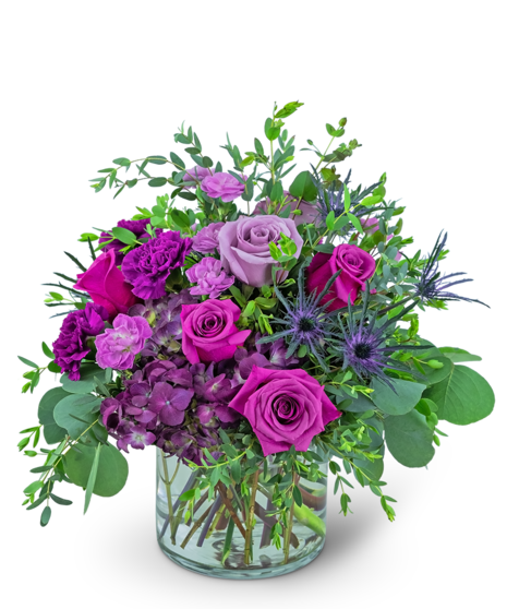 magenta flowers with green filler around them in a low glass container